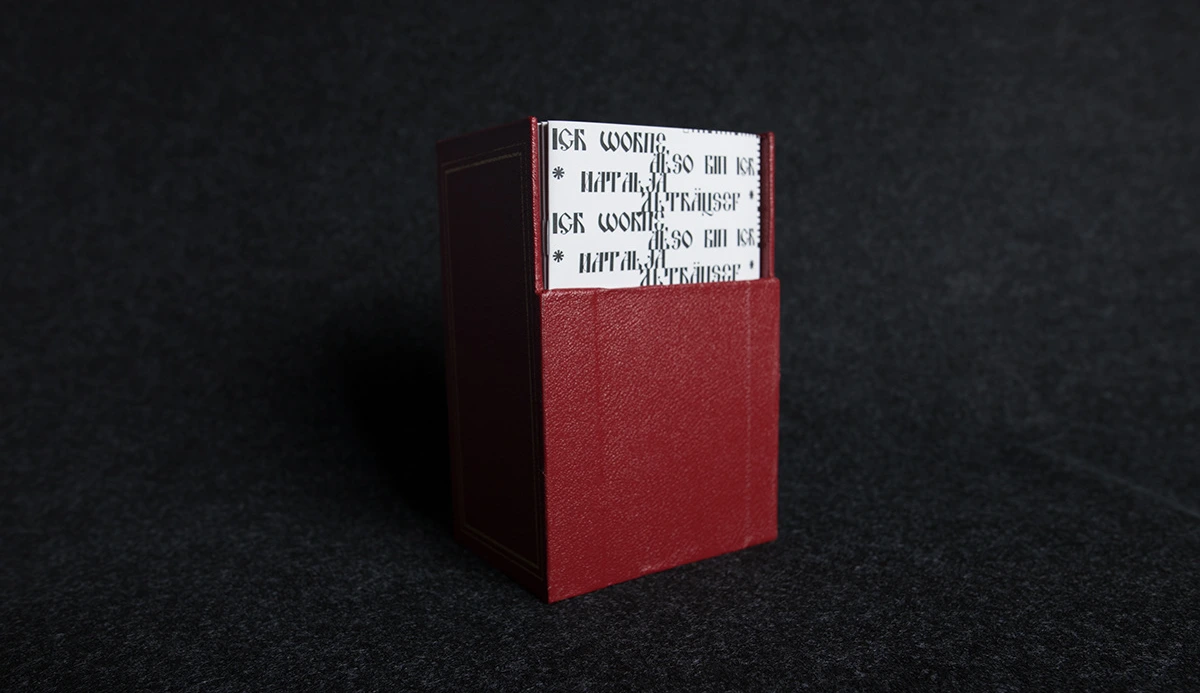 Red slipcase upright with the booklets peeking out from the top.